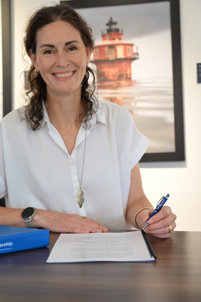 Donor smiles while signing gift documents at a desk