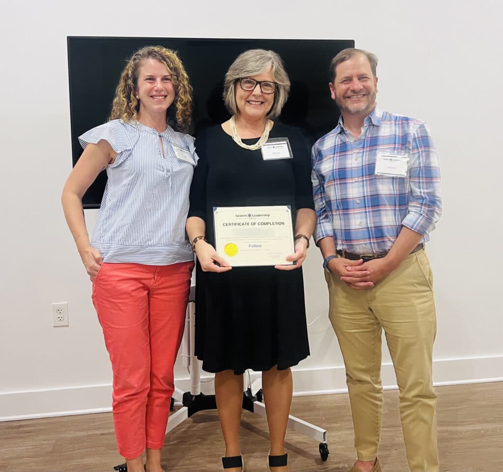 Graduating Fellow holds her certificate alongside two mentors at a Severn Leadership Group ceremony