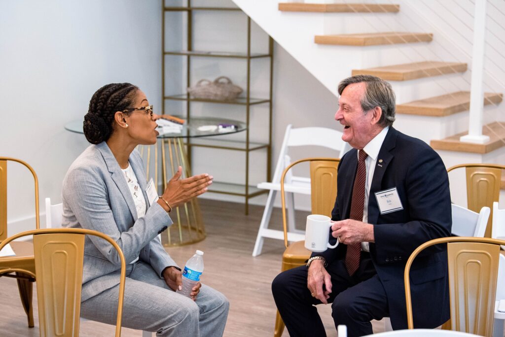 Mentor and Fellow talk while seated together at a Severn Leadership Group graduation reception in Annapolis