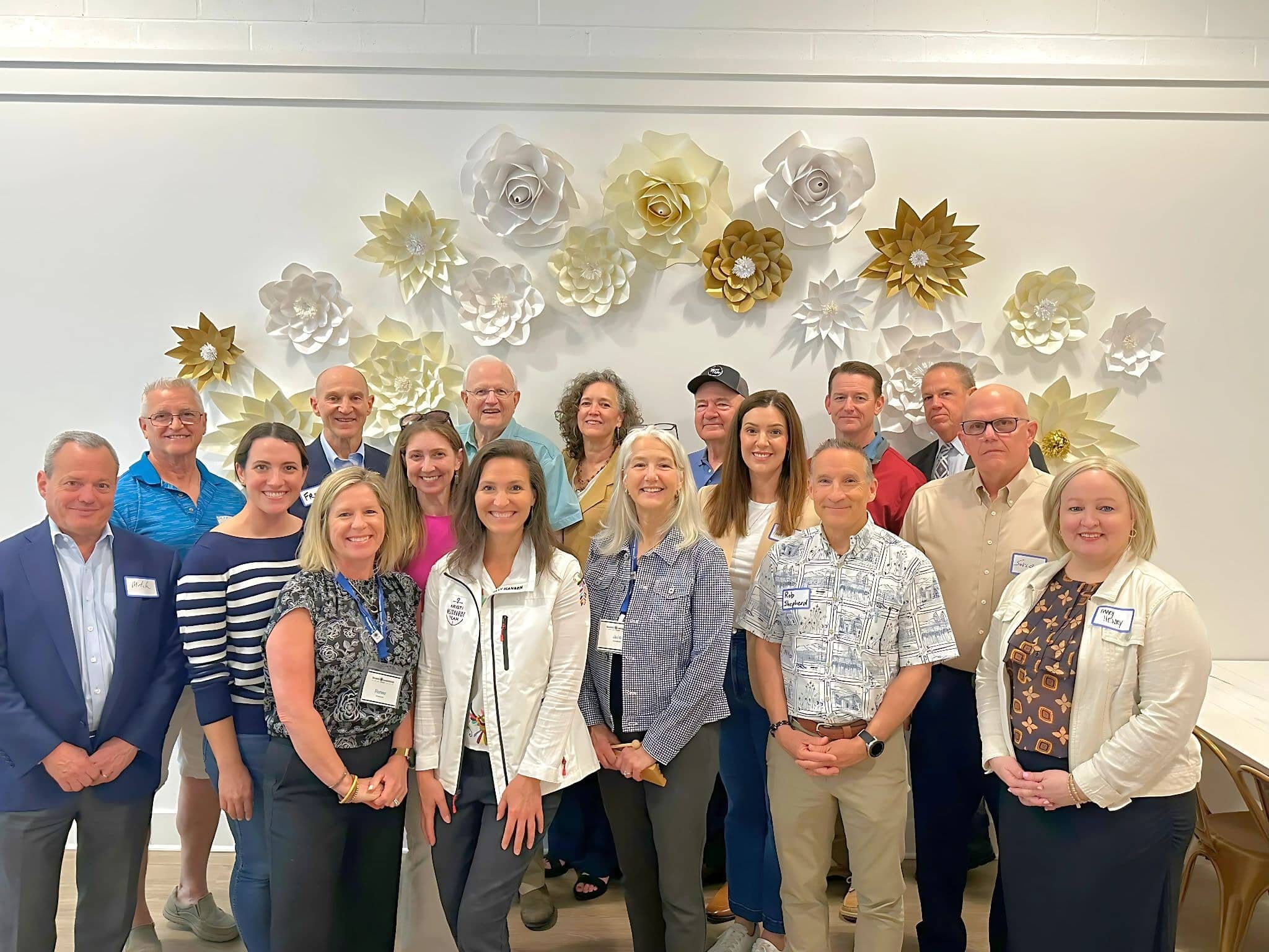 Mentors and Fellows wearing name tags gather for a group photo in front of a paper flower wall