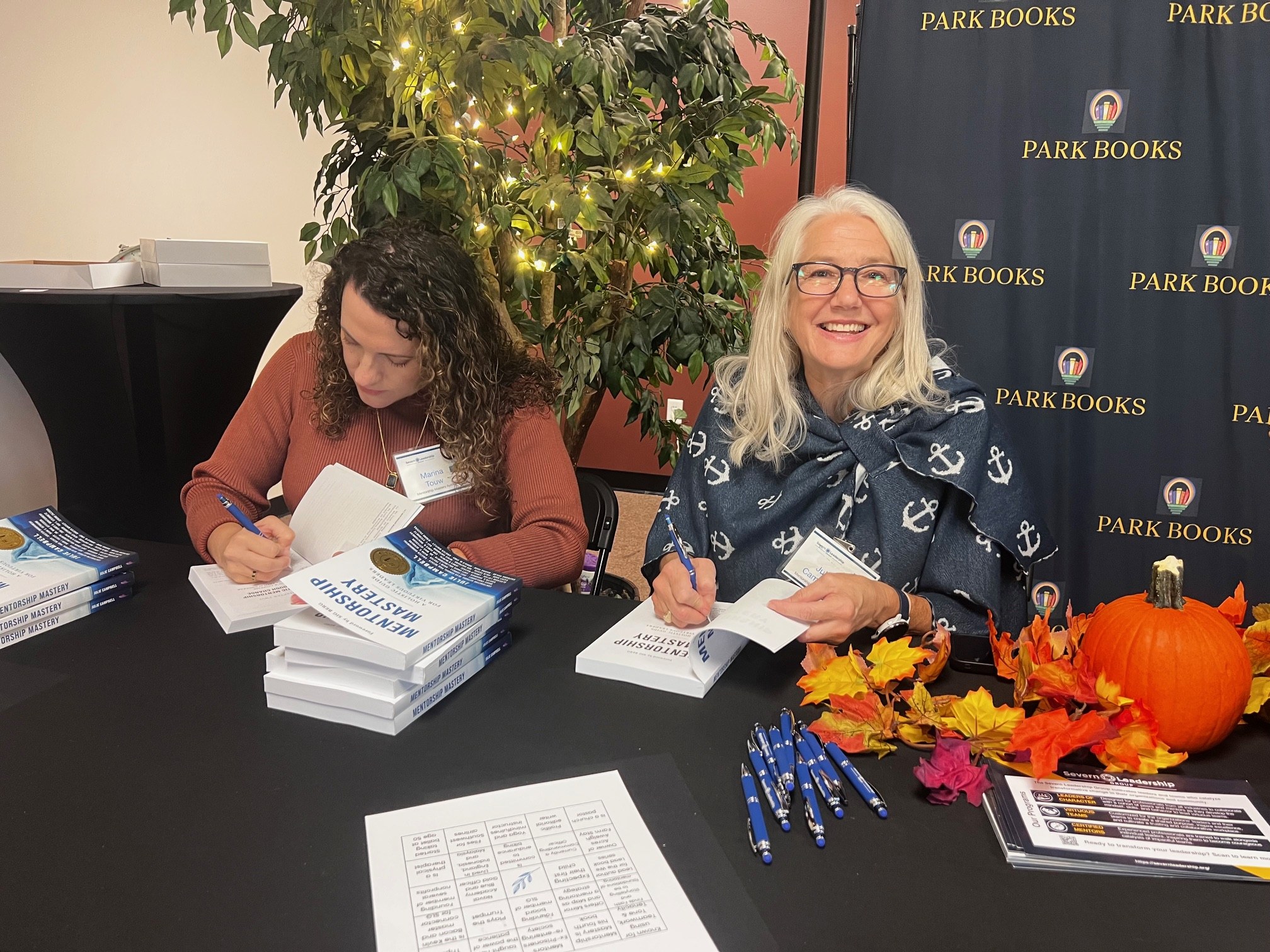 Two women sign copies of Mentorship Mastery at a Severn Leadership Group book signing at Park Books