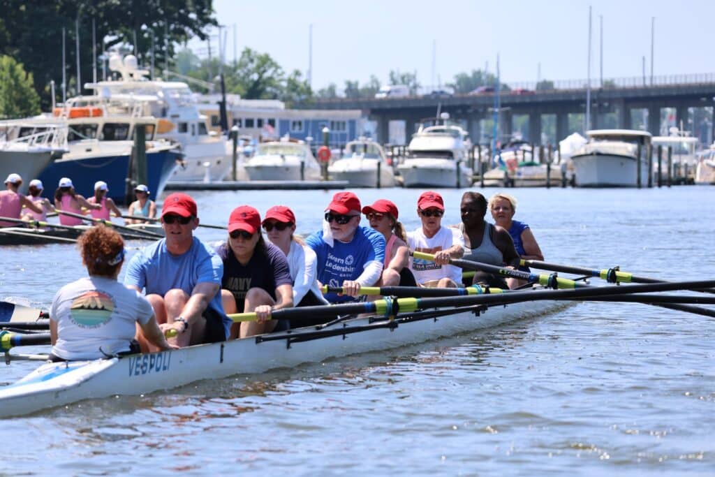 rowing crew pulling together on the water near a marina