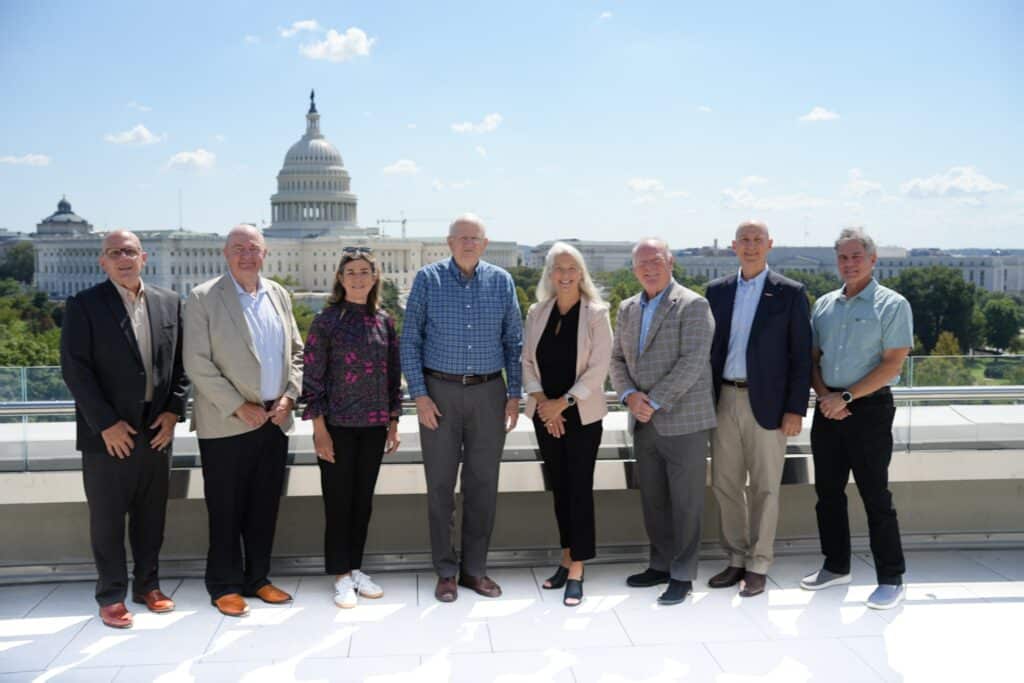 Severn Leadership Group board members stand on a rooftop terrace with the U.S. Capitol behind them