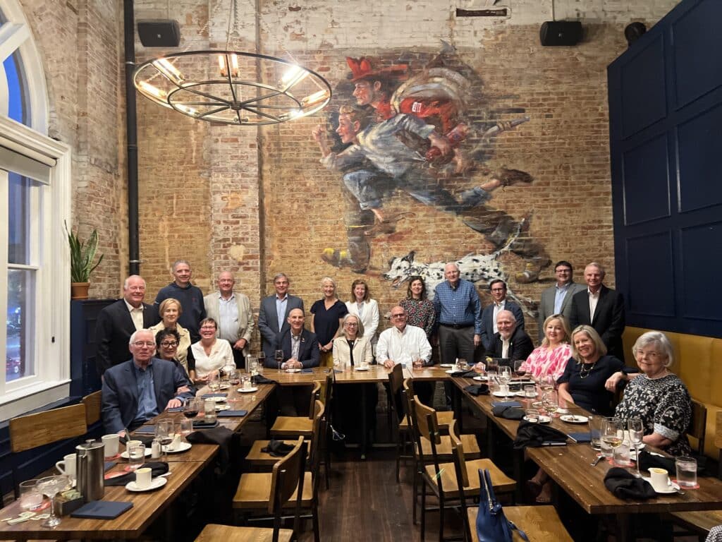 Severn Leadership Group members gather around long dining tables for a group photo at a dinner event